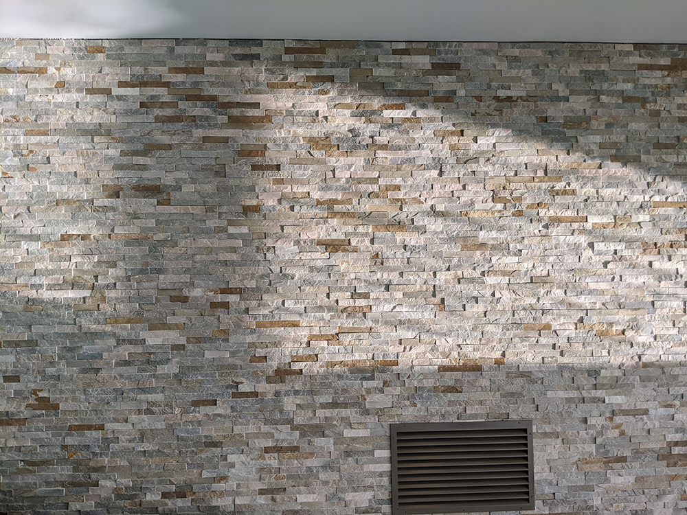 A photo of the newly tiled wall with the painted ventilation grille.