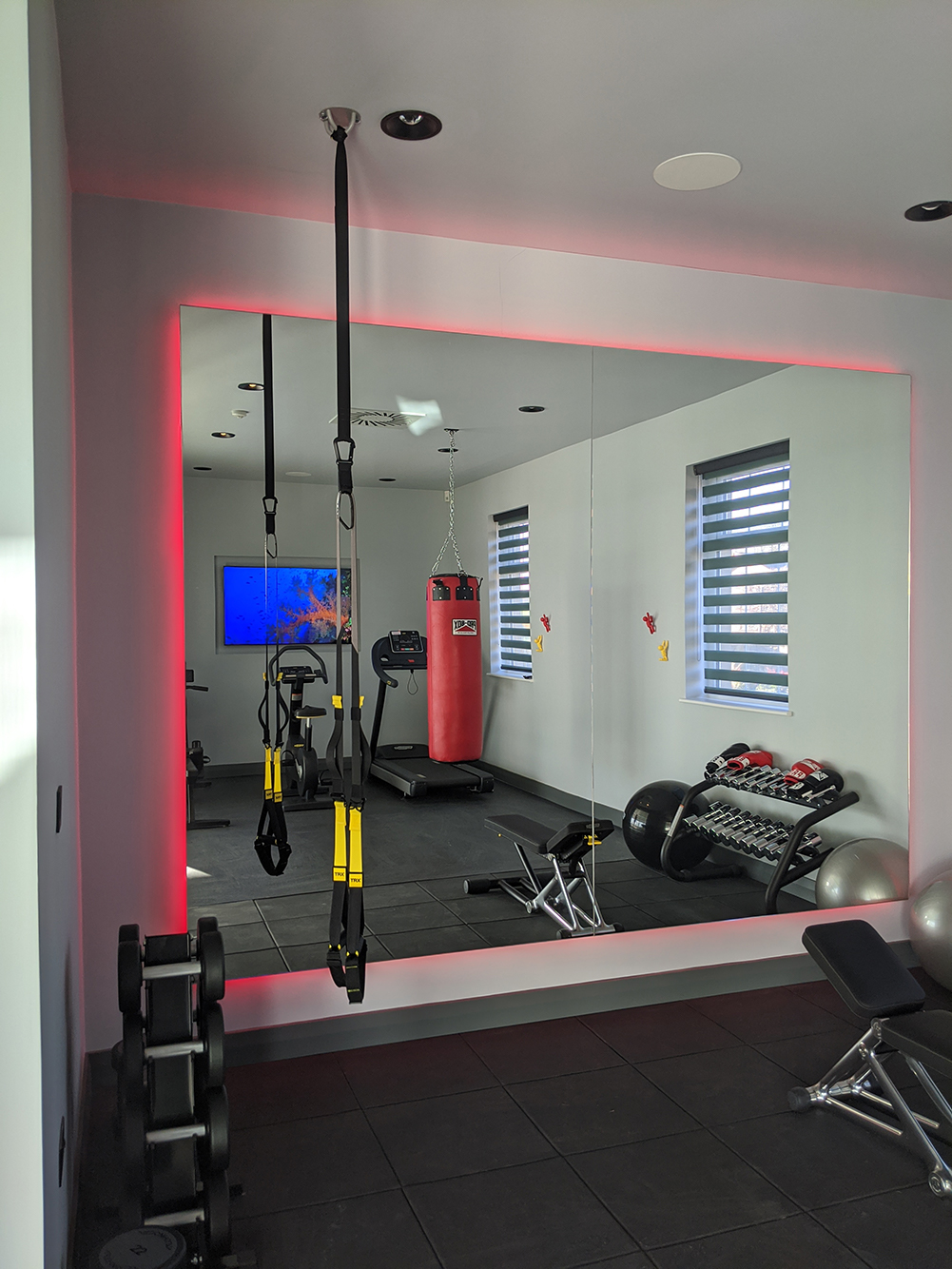 A photo of the finished gym with red LED lighting around the mirror.