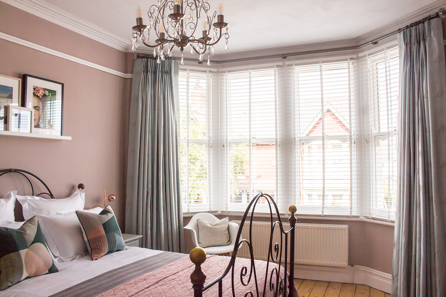 A wide shot of a pink bedroom with a traditional bay window