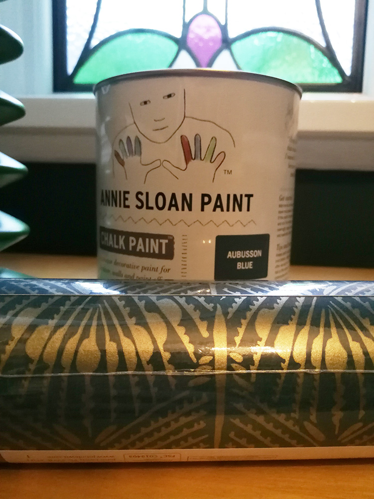 the roll of wallpaper I used, im front of the tin of paint I used