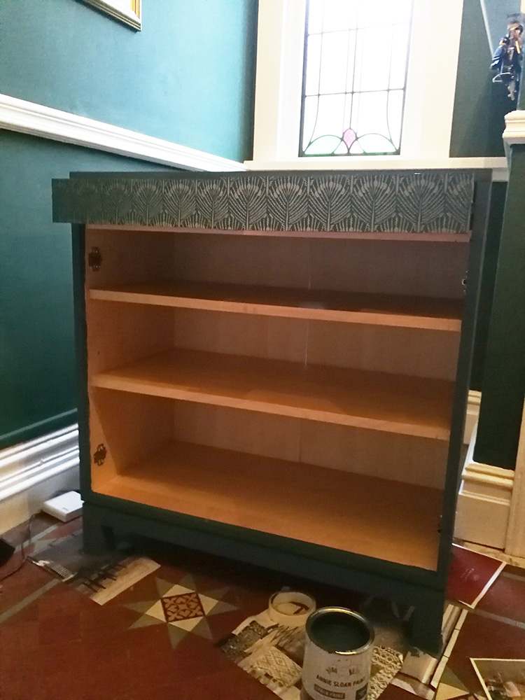 a photo of the cupbaord with the wallpaper on the drawer fronts