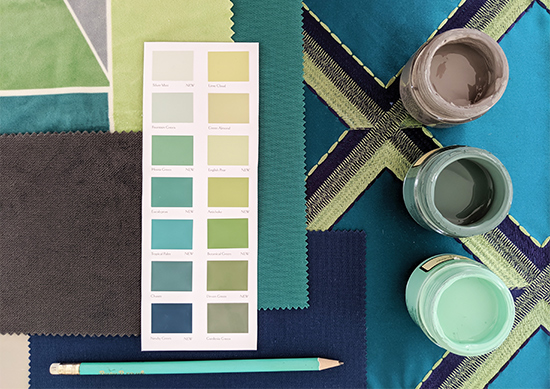 A selection of paints, fabrics and a paint chart arranged together.